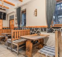 Szállodák és panziók belső tere rusztikus fa padokkal és asztallal, dekoratív kő a falon.