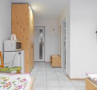 Panzió belső tere ágyakkal, televízióval, szekrénnyel, mikrohullámú sütővel és hűtőszekrénnyel.