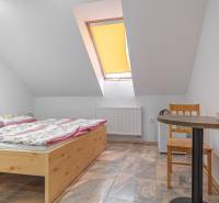 Szoba szállodákban és panziókban faasztallal, virágos ágyneművel és ferde ablakkal.