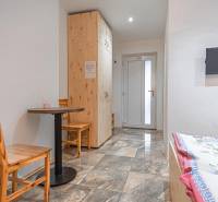 Szoba szállodákban és panziókban csempével, fa asztallal, székekkel, TV-vel és ággyal.