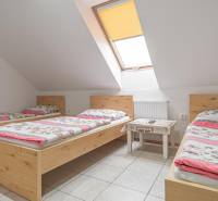 Három ágy színes ágyneművel, asztal, tetőablak szállodákban és panziókban.