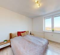 Világos hálószoba fa mintázatú padlóval és nagy ablakkal egy háromszobás lakásban.