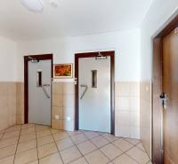 Folyosó több ajtóval és egy képpel egy háromszobás lakásban, csempe a padlón.