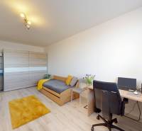 Szoba egy háromszobás lakásban, fa dekorációjú padlóval, ággyal és íróasztallal.