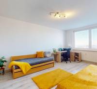 Világos szoba ággyal, íróasztallal és fa dekorációjú padlóval egy háromszobás lakásban.