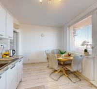 Konyha egy háromszobás lakásban étkezőasztallal és fa dekoros padlóval.