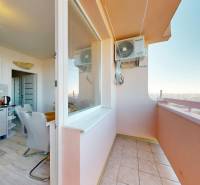 Konyha étkezővel és erkéllyel egy háromszobás lakásban, fa dekor padlóval.