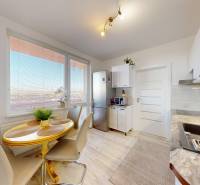 Konyha egy 3 szobás lakásban világos padlóval és étkezőasztallal.