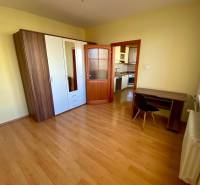 Hálószoba egy háromszobás lakásban, fa mintázatú padlóval, gardróbszekrénnyel és íróasztallal.