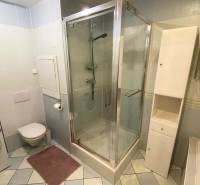 Fürdőszoba egy háromszobás lakásban mosógéppel, zuhanyzóval és fehér bútorokkal.