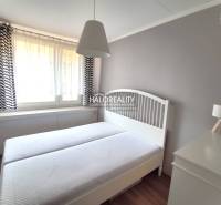 Hálószoba egy kétszobás lakásban fehér bútorokkal és finom függönyökkel.