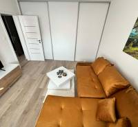 Nappali egy kétszobás lakásban, fa mintázatú padlóval és narancssárga kanapéval.