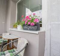 3 szobás lakás erkélye virágokkal és asztallal, ideális a pihenésre.