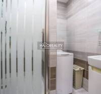 Fürdőszoba mosógéppel és zuhanyzóval egy háromszobás lakásban, világos csempék, tiszta dizájn.