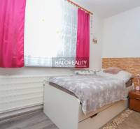 Szoba egy háromszobás lakásban ággyal, virágos függönnyel és fa dekorációjú padlóval.