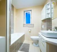 Fürdőszoba káddal és mosdóval egy kétszobás lakásban, világos csempe dominál.