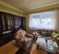 Családi ház nappalija színes kanapéval és sötét nappali szekrénnyel.