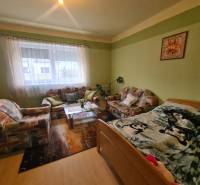 Nappali egy családi házban kanapéval, szőnyegekkel és dekoratív képpel a falon.