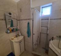 Fürdőszoba családi házban, zuhanyfülke függönnyel, mosdó, tükör és radiátor.