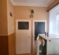 Családi ház belső tere két ajtóval, hűtőszekrénnyel és fa dekorációjú padlóval.