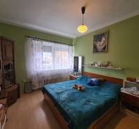 Hálószoba családi házban fa dekorációjú padlóval és ággyal.