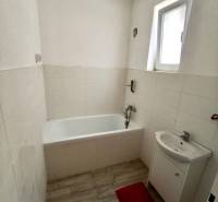 Fürdőszoba családi házban káddal, mosdóval és fa mintázatú padlóval.