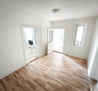 Szoba egy családi házban, fa dekoros padlóval és egyszerű berendezéssel.