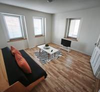 Nappali családi házban kanapéval, televízióval és fa dekorációjú padlóval.