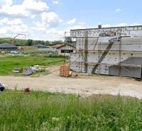 Építési telek lakóház céljára Modrovkán, félkész épülettel és háttérben lévő környezettel.