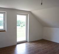 Világos szoba ablakokkal, fa dekoros padlóval és üvegajtókkal a családi házban.