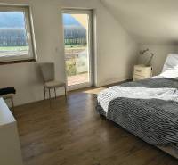 Világos hálószoba családi házban, ággyal, székkel és fa dekorációjú padlóval.