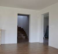 Családi ház belső tere kandallóval, lépcsővel és fa dekorációjú padlóval.