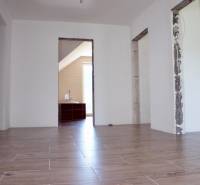 Családi ház belső tere fa dekorációjú padlóval és fedetlen építési nyílásokkal.