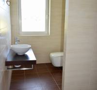 Fürdőszoba családi házban világos mosdóval és fa mintázatú padlóval.