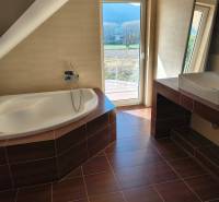 Családi ház fürdőszobája káddal és fa dekorációjú padlóval.