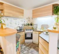 Konyha egy családi házban sarok konyhabútorral és fa dekorációval, dekoratív növényekkel a polcokon.