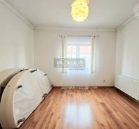 Egy családi házban lévő szoba fa dekorációjú padlóval, világos díszítéssel és nagy ablakkal.