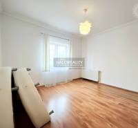 Tágas szoba fa dekor padlóval és világos berendezéssel egy családi házban.