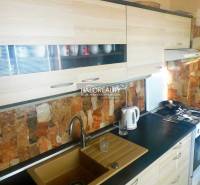 Szoba egy kétszobás lakásban fa dekoros padlóval, televízióval és beépített szekrényekkel.