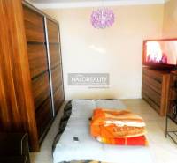 Hálószoba egy kétszobás lakásban ággyal, kanapéval és fa dekoros szekrénnyel.