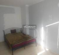 Hálószoba fém ággyal és fehér falakkal egy kétszobás lakásban.