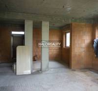 Egy családi ház befejezetlen belső tere, látszó téglafalakkal és betonpadlókkal.