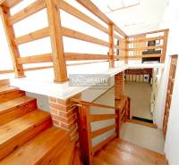 Fa lépcsők és korlátok családi házban tégladíszítéssel a falon.