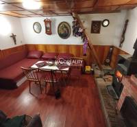 Rusztikus faház, fából készült mennyezet, kandalló, kényelmes ülőgarnitúra, hagyományos belső tér, kellemes légkör.