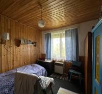 Egy szoba családi házban, fa burkolatú falakkal, kék szekrénnyel és ággyal.