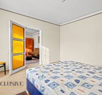 Hálószoba családi házban ággyal, székkel és narancssárga üveges ajtóval.