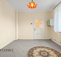 Világos szoba családi házban, szőnyeggel és csipkefüggönyös ablakkal.