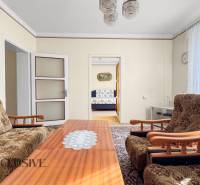 Családi ház nappalival, virágos bútorokkal, dohányzóasztallal és képpel a falon.