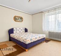 Hálószoba családi házban, szőnyeggel, nagy ablakkal és radiátorral.