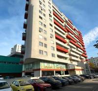 Lakóház a pozsonyi Martinčekova utcában parkolóval és erkélyekkel, napos égbolt.